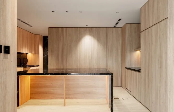 Isla de cocina moderna en roble claro con remate de mármol negro y luces empotradas en Burgos