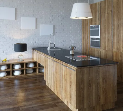Isla de cocina en madera clara con encimera negra, campana blanca y cafetera moka en Burgos