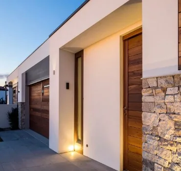 Fachada de vivienda con puerta principal y garaje en madera oscura en Burgos