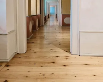 Pasillo largo con suelo de tarima de madera de pino clara instalada, perspectiva de fuga en Burgos