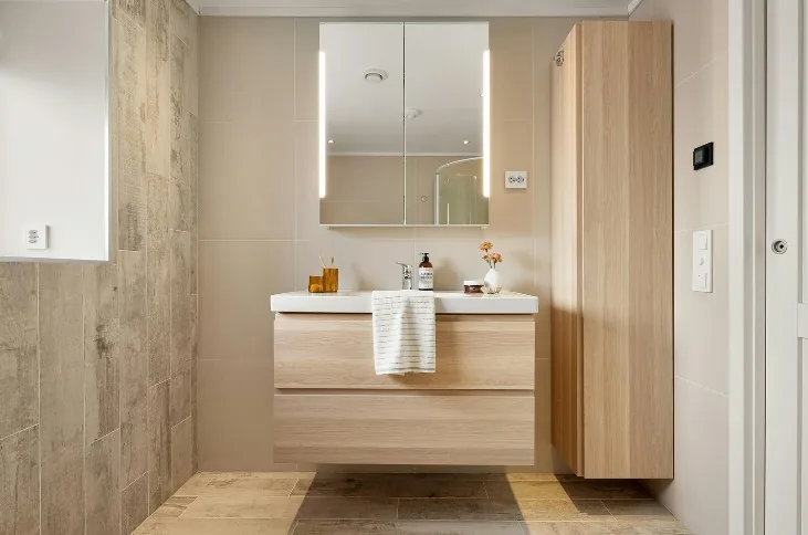 Mueble de baño flotante en roble claro con cajones, armario columna alto y espejo con luz en Burgos