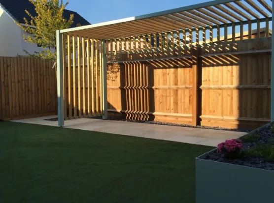 Pérgola moderna de lamas de madera clara junto a valla en un chalet de Castañares