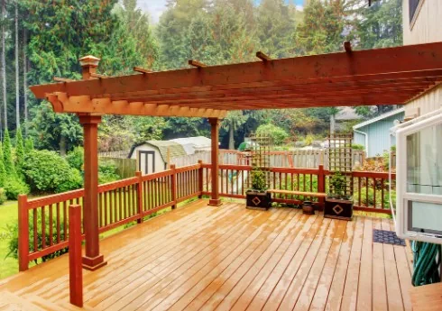 Terraza de madera con pérgola y jardín trasero en un adosado de Villímar