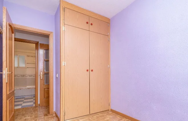 Puerta de armario empotrado en madera clara con tiradores rojos junto a puerta de paso de madera en Burgos