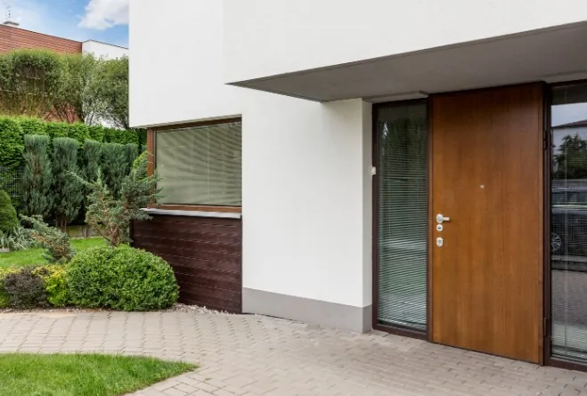 Puerta de entrada en madera de roble en fachada blanca moderna con jardín, en Gamonal, Burgos