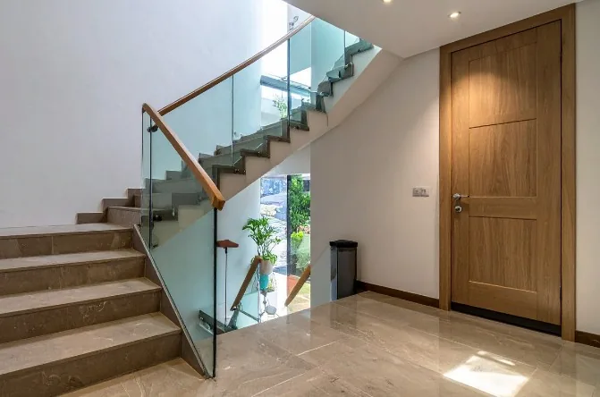 Recibidor con escalera de mármol y puerta de entrada en madera de roble claro en Burgos