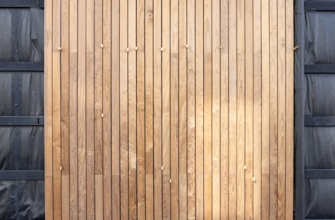 Fachada revestida con listones verticales de madera clara entre paneles metálicos oscuros en Burgos