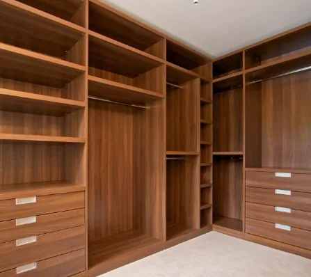 Interior de armario ropero de madera color nogal con baldas, barras y cajoneras con tiradores metálicos en Burgos