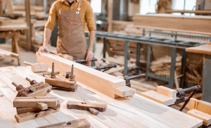 Carpintero restaurando la estructura de un mueble de madera con prensas artesanales en el taller de Burgos